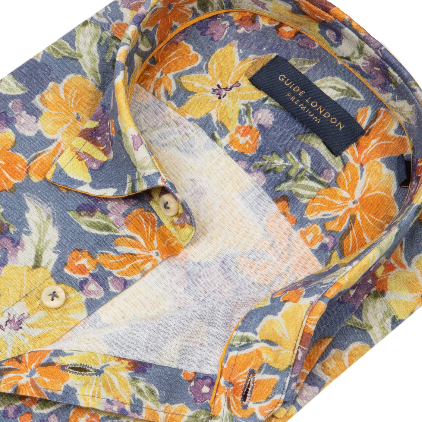 A detailed picture featuring a Folded Tropical Paradise Long Sleeve Shirt with yellow, orange and navy floral pattern on White Background