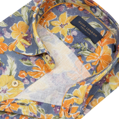 A detailed picture featuring a Folded Tropical Paradise Long Sleeve Shirt with yellow, orange and navy floral pattern on White Background
